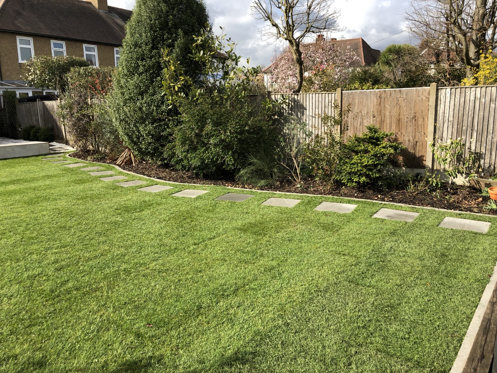 Back garden lawn with stepping-stone path and tidy borders