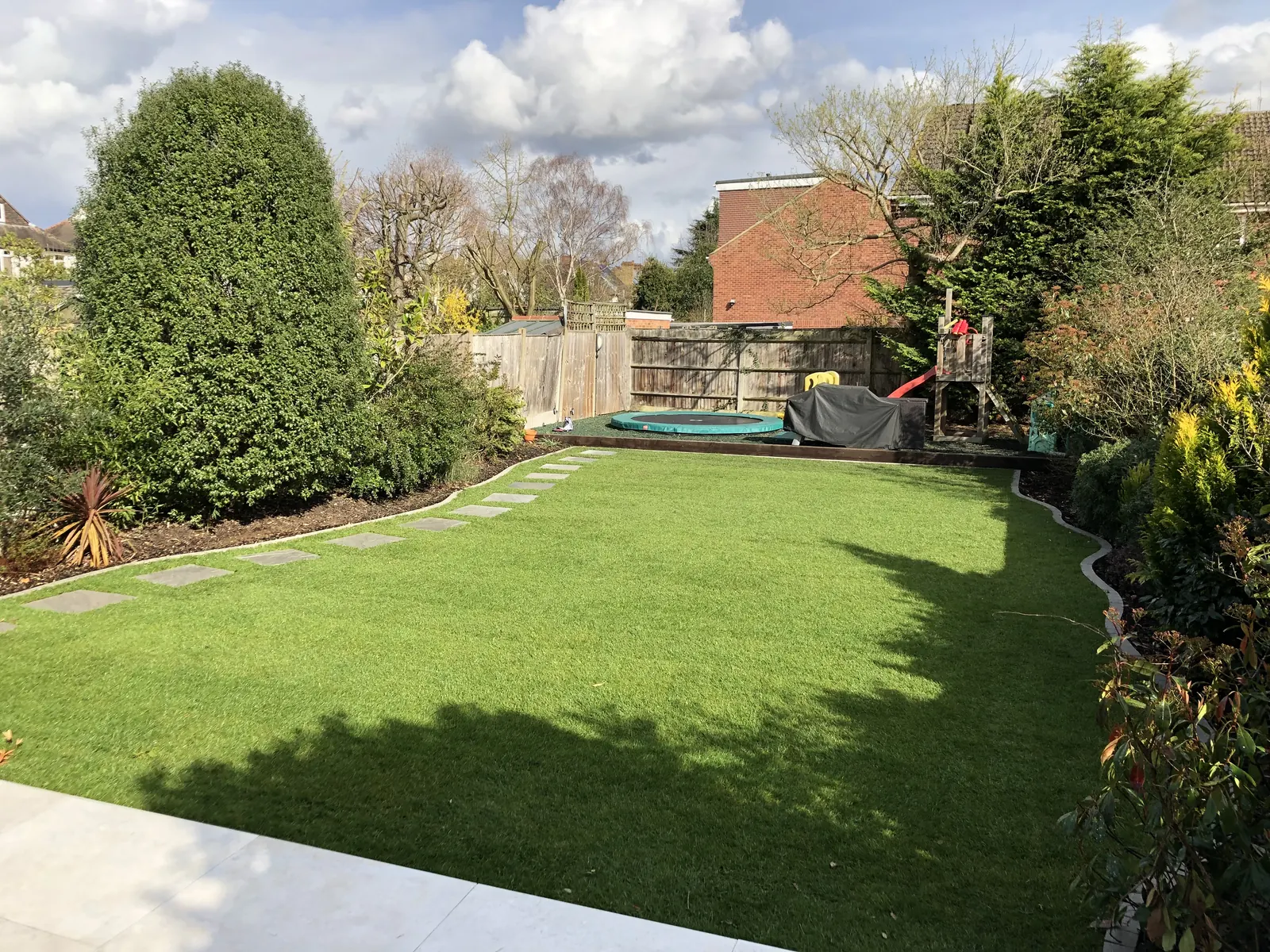 Manicured garden lawn with stepping-stone path and mature borders