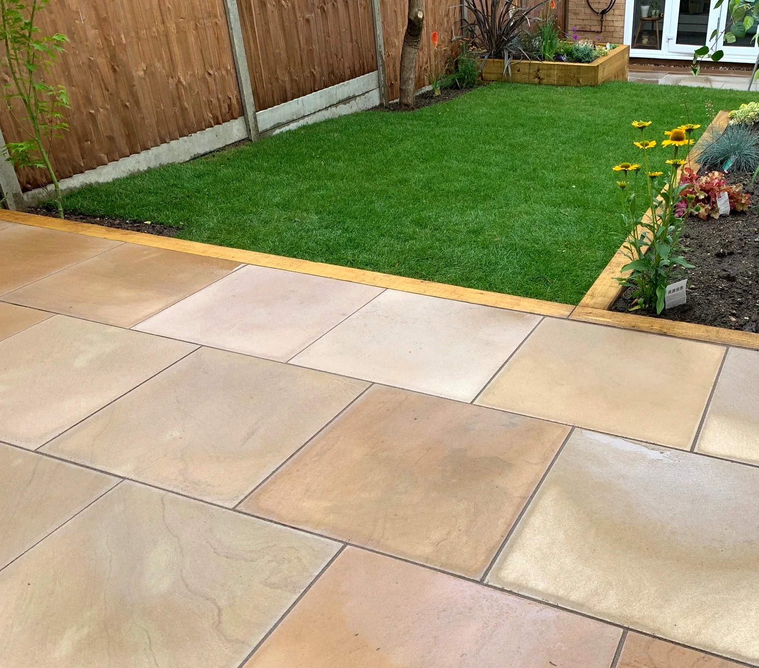 Sandstone patio with lawn and flower beds transformation
