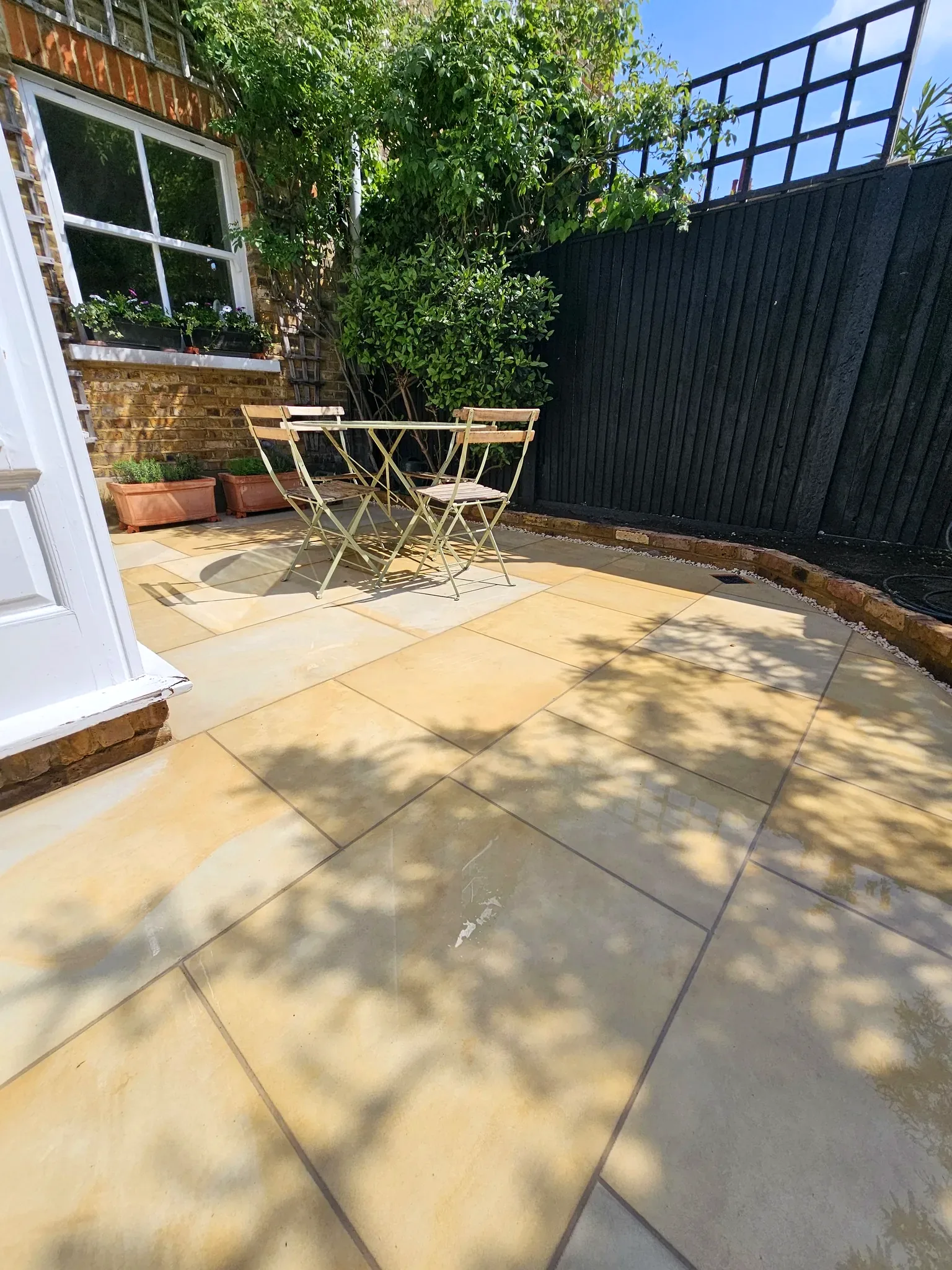 Shaded sandstone patio with bistro seating in Twickenham
