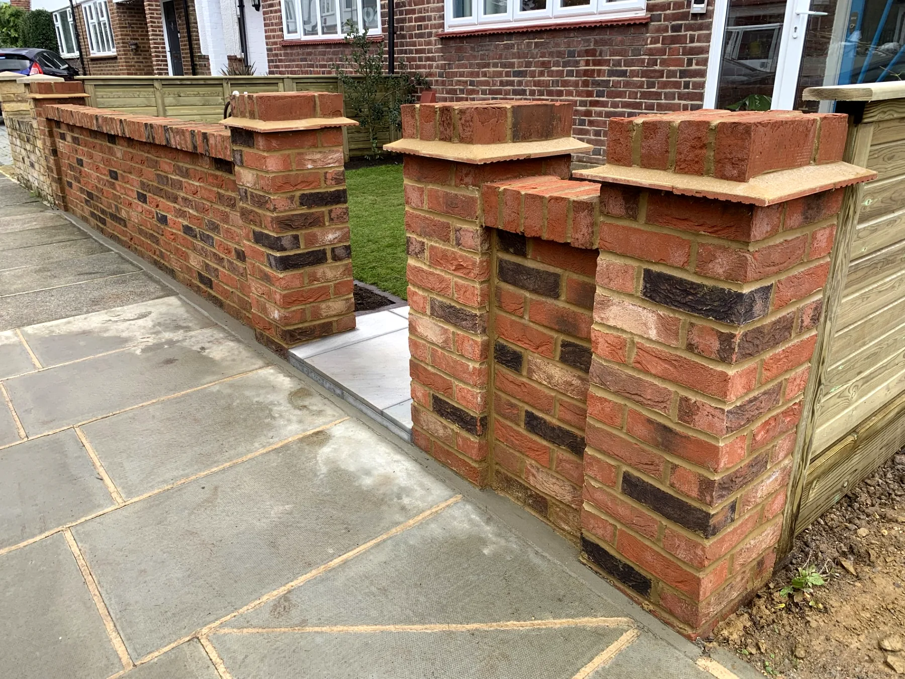 Red brick wall with multiple pillars and sandstone copings